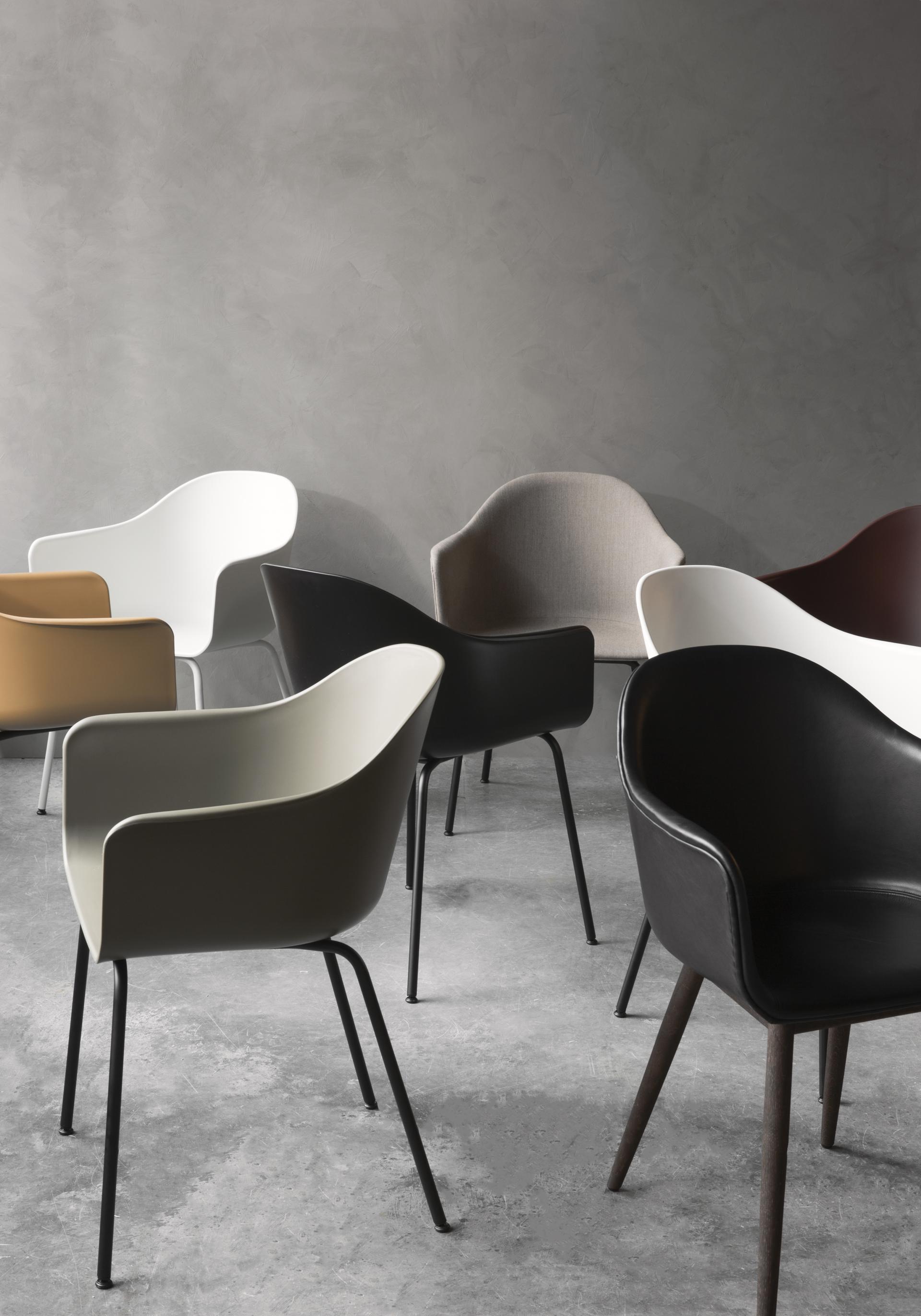 Contemporary designer chairs in various colors arranged against a minimalist backdrop, showcasing modern interior design trends.