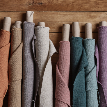 New spring colors of Camira's Yoredale bouclé fabric displayed on wooden surface, showcasing a vibrant range of British wool textiles.