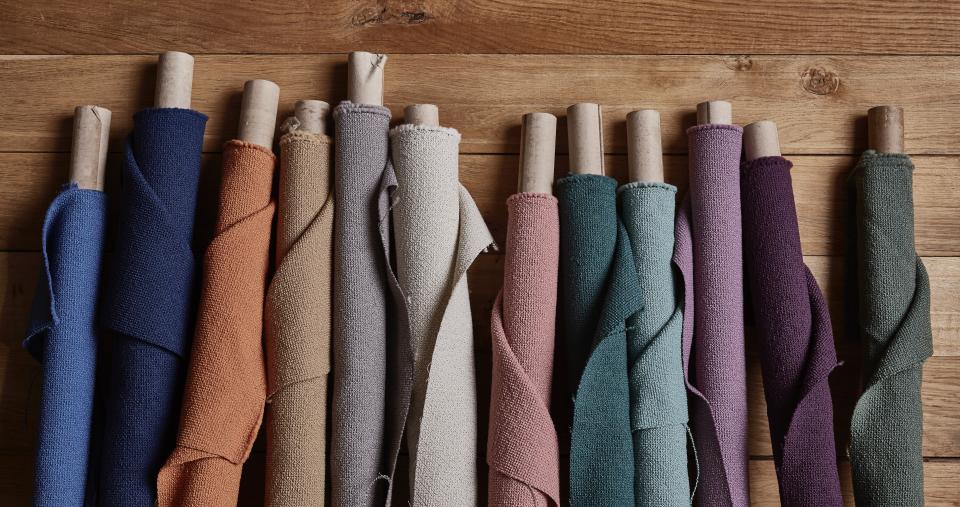 New spring colors of Camira's Yoredale bouclé fabric displayed on wooden surface, showcasing a vibrant range of British wool textiles.