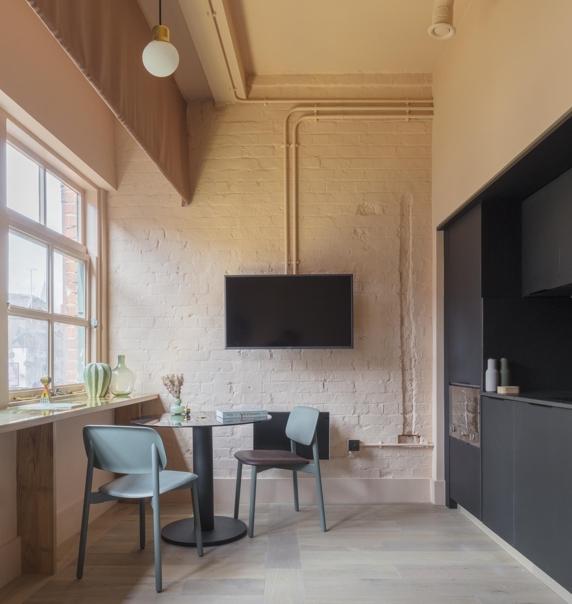 Stylish interior of Whitworth Locke aparthotel featuring a cozy dining area, wall-mounted TV, and modern décor.