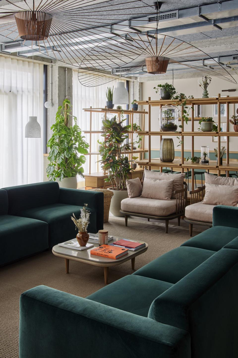 Sophisticated lounge area in WunderLocke, featuring plush green sofas, stylish lighting, and abundant greenery, designed by Holloway Li.