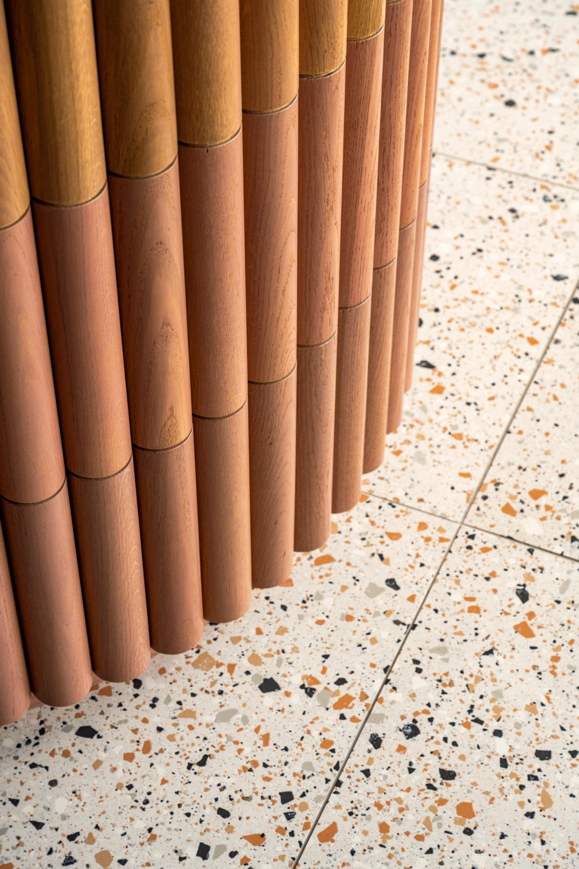 Natural wood columns adjacent to a speckled terrazzo floor, highlighting craftsmanship in Dentons' Edinburgh workspace design.