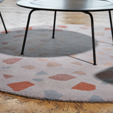 Circular area rug with abstract patterns under a modern black table and chair, highlighting contemporary interior design.