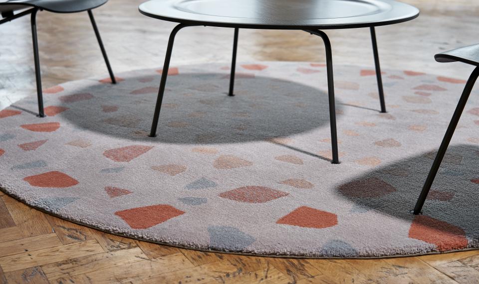 Circular area rug with abstract patterns under a modern black table and chair, highlighting contemporary interior design.