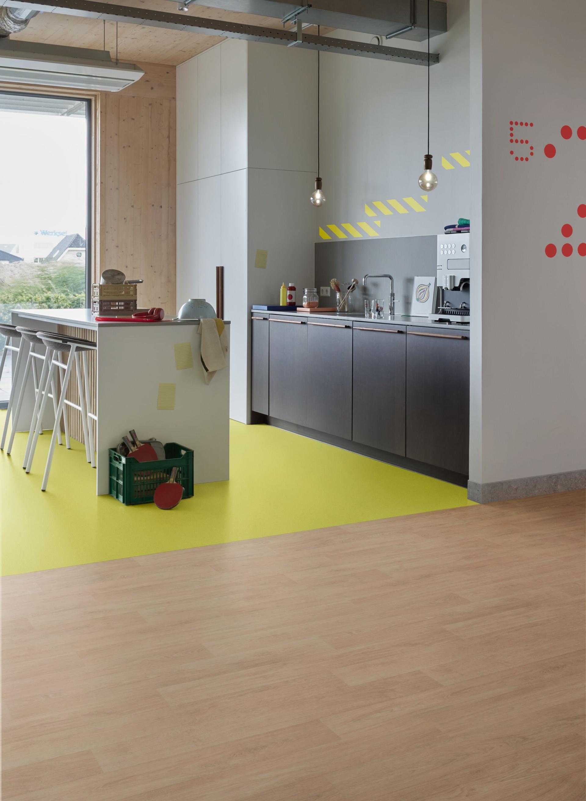 Modern kitchen showcasing Forbo's Modul’up flooring with vibrant yellow and wood finishes, highlighting refurbishment and design innovation.