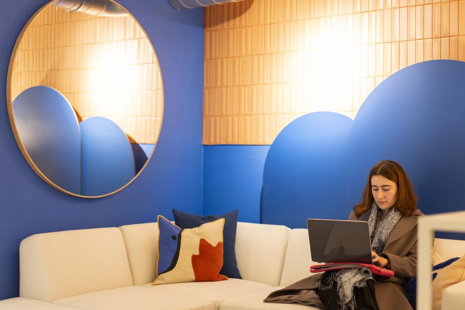 A woman working on a laptop in a stylish, colorful lounge at Material Source Studio Manchester.