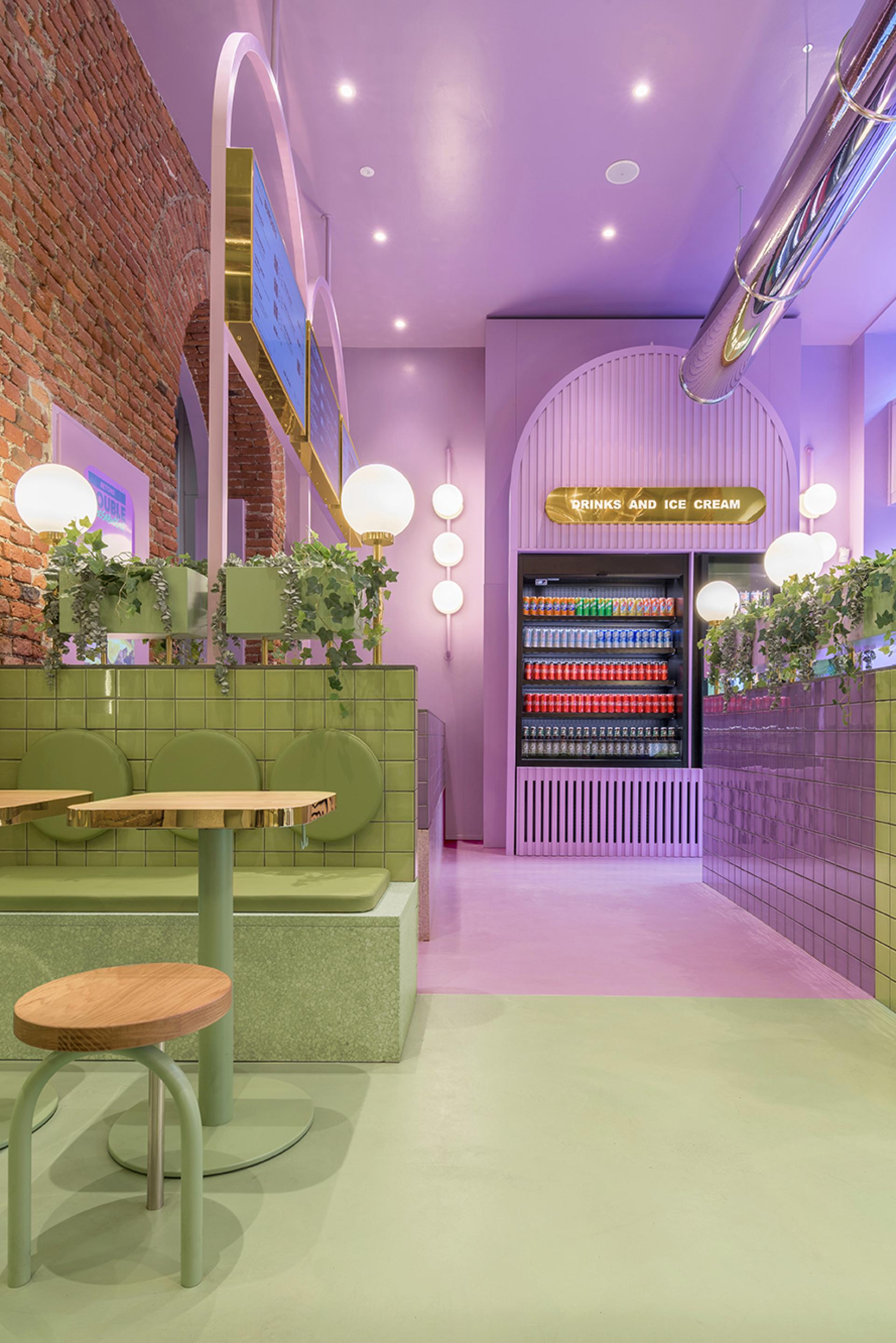 Colorful interior design of Bun restaurant in Milan, featuring green seating, pink floors, and stylish light fixtures.