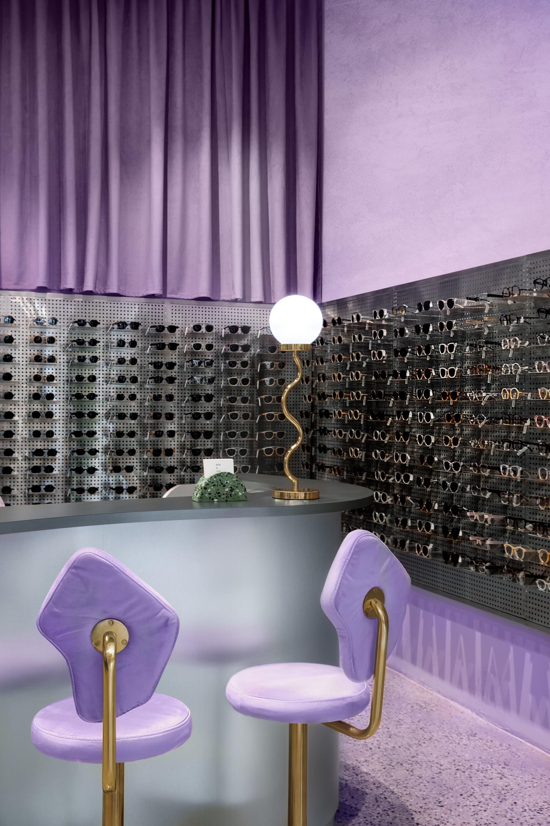 Interior of a trendy eyewear store showcasing sunglasses and frames, featuring stylish purple decor and modern display elements.