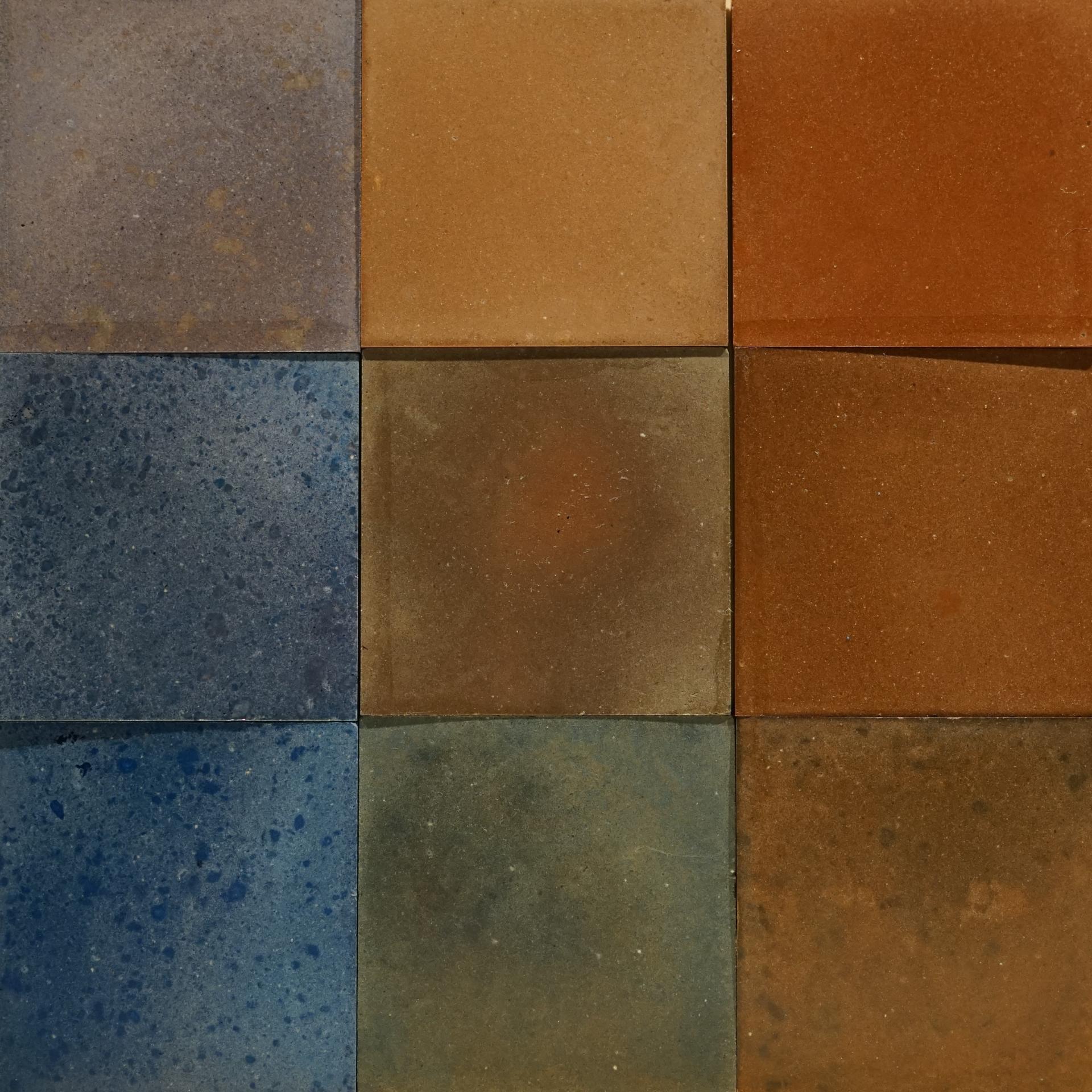 Colorful ceramic tiles arranged in a square, showcasing various textures and earthy tones, highlighting DeakinBio's innovative design approach.