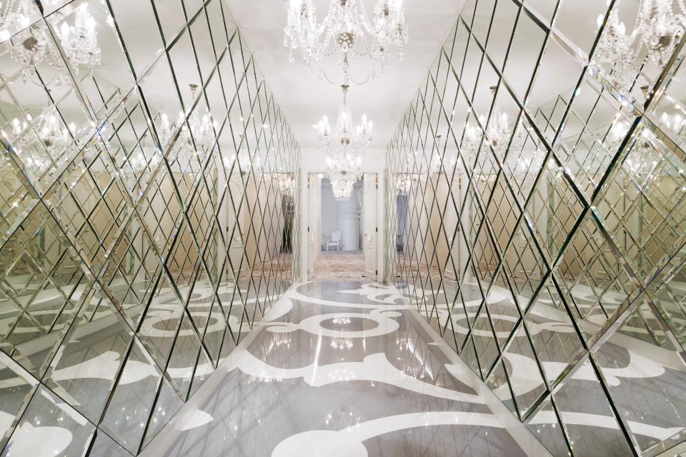 Reflective hallway in Mondrian Doha hotel with intricate mirrors, elegant chandeliers, and stylish patterned flooring designed by Marcel Wanders.