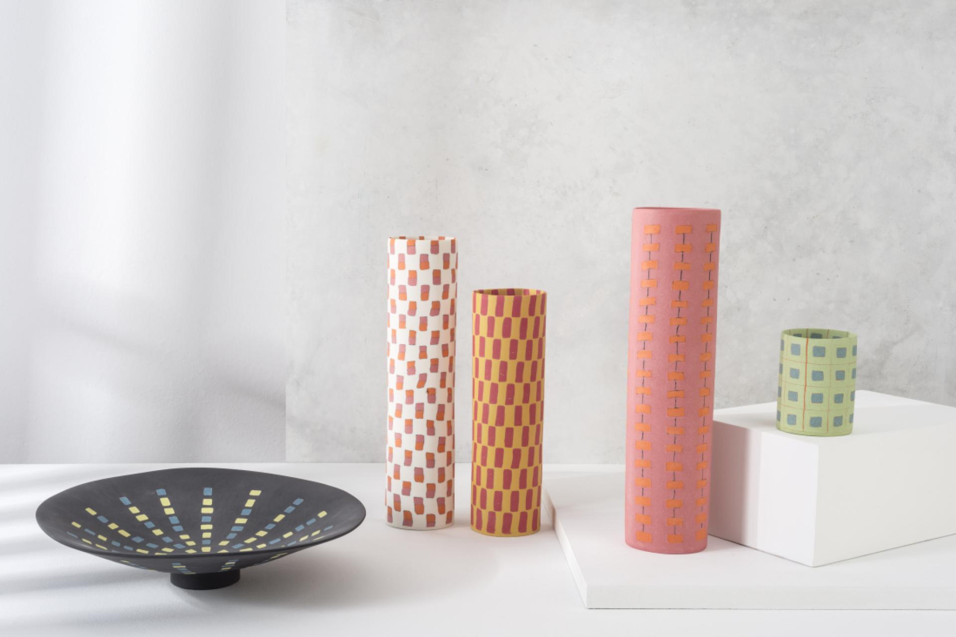 Colorful modern pottery pieces and a decorative bowl on a light gray background, showcasing craftsmanship from London Craft Week 2024.