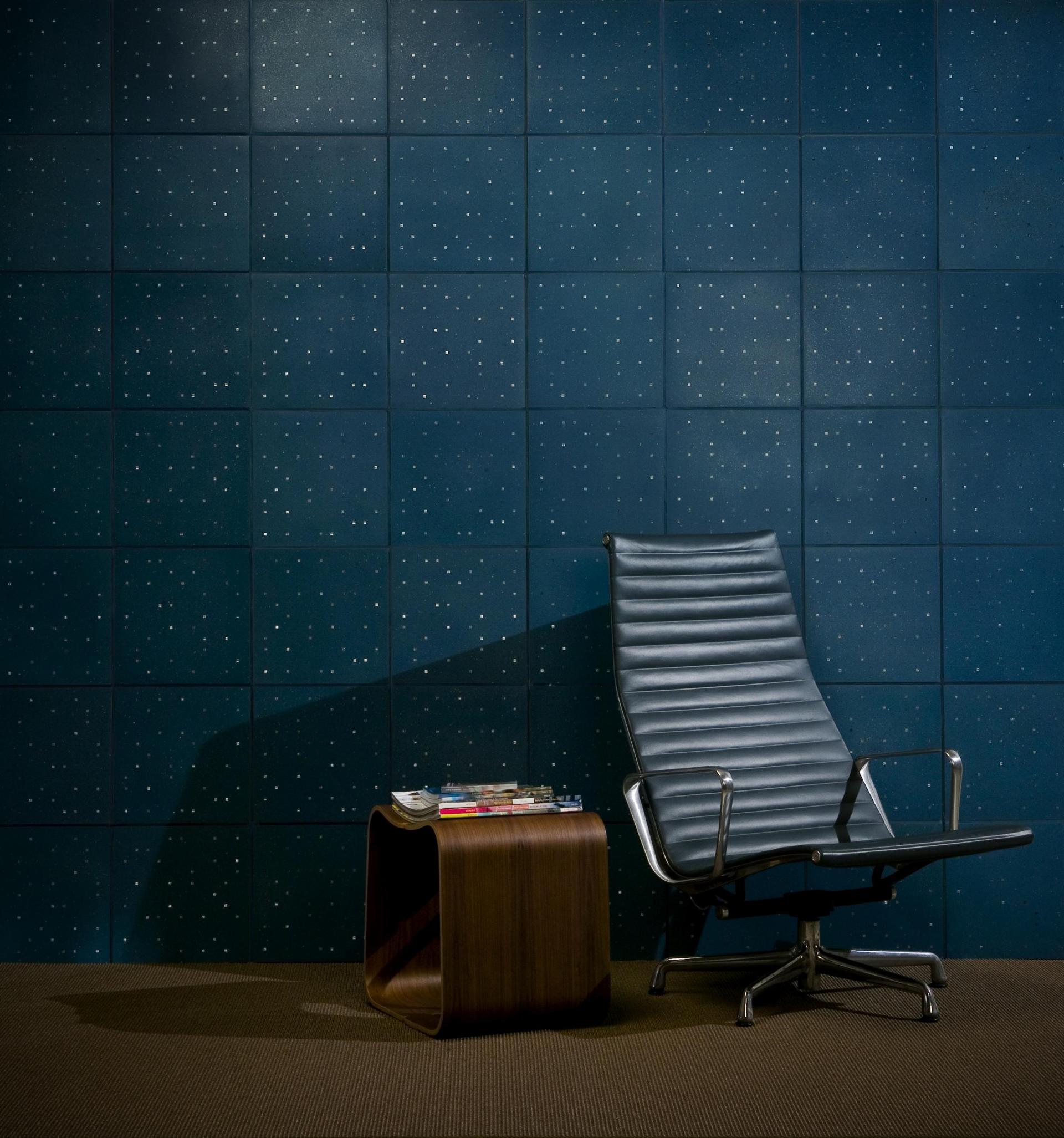 Elegant chair and modern side table against a starry-patterned blue wall, showcasing innovative design and sustainable aesthetics.