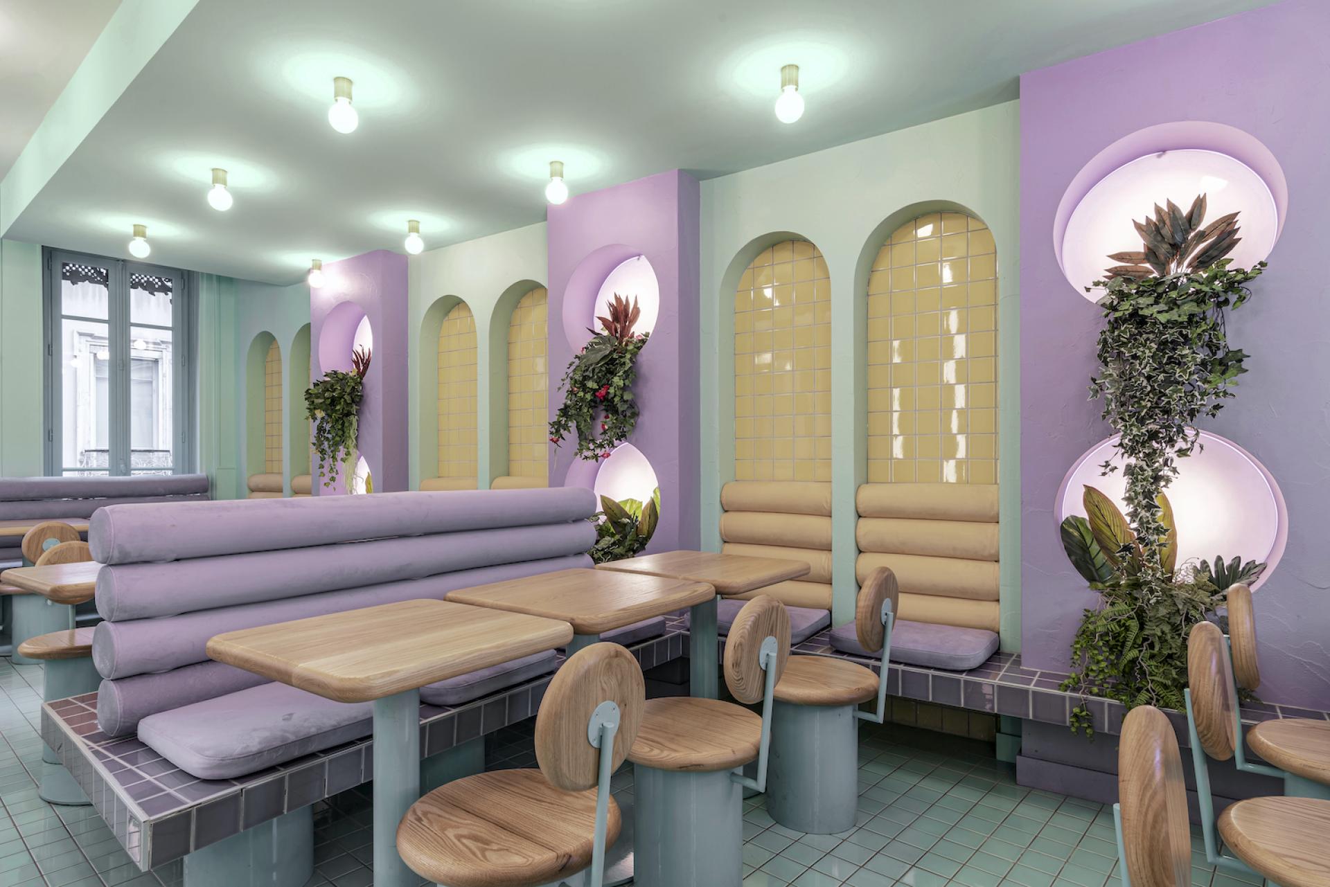 Brightly colored interior of Piada's new Lyon shop featuring pastel seating, greenery, and stylish lighting design by Masquespacio.