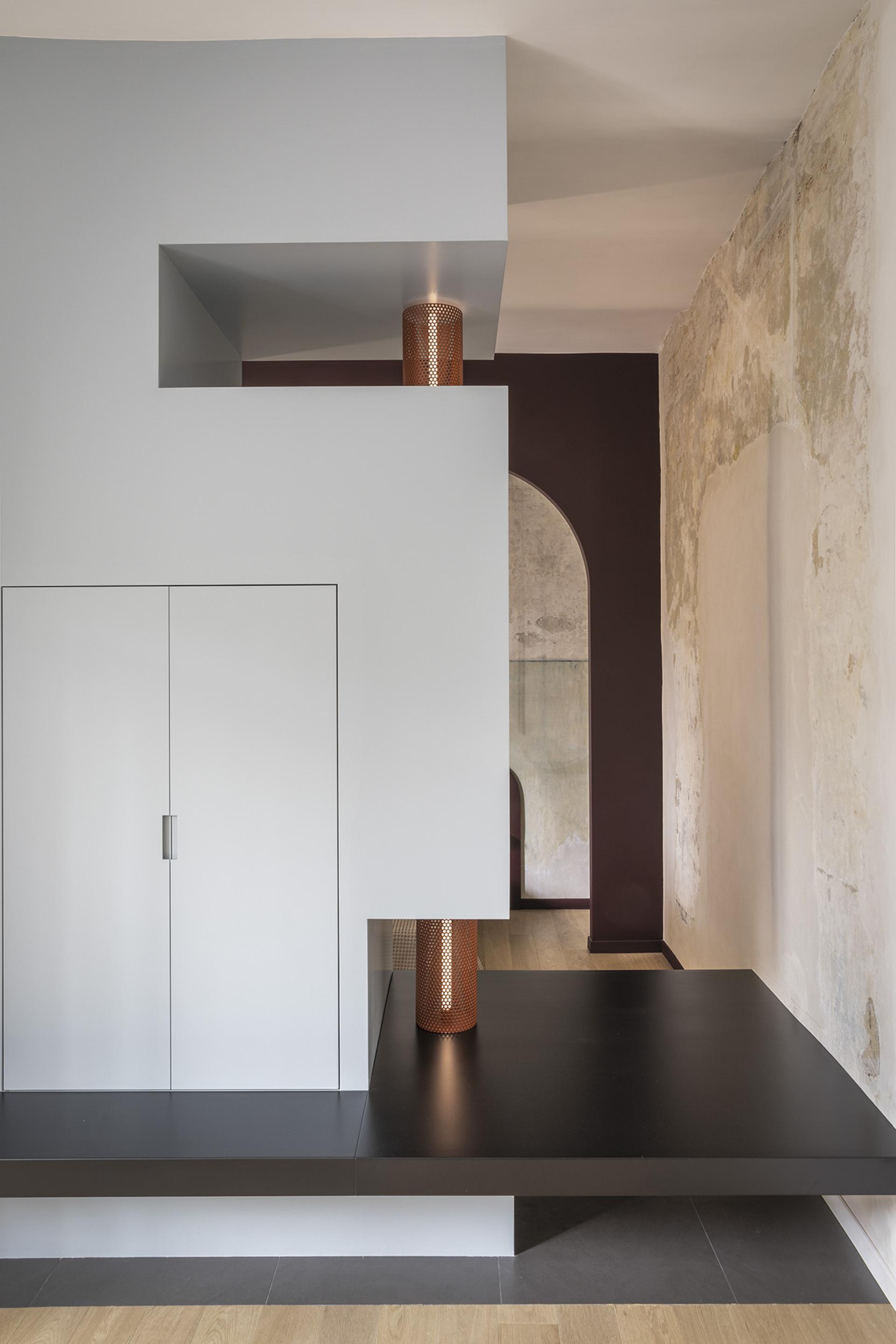 Modern interior design of a compact Trastevere apartment featuring sleek surfaces, copper accents, and an artistic archway.