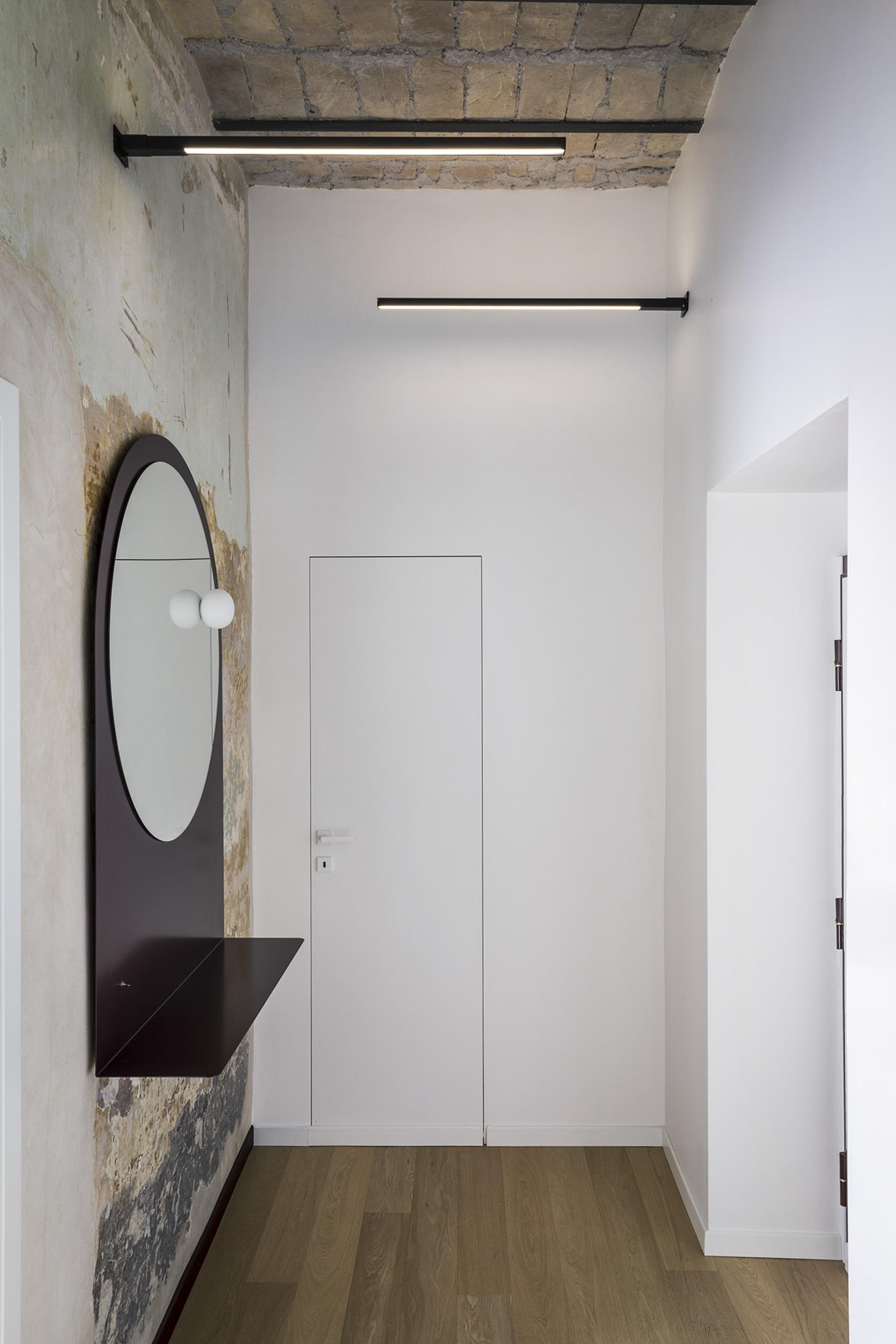 Modern entryway of a stylish 65-square-meter apartment in Trastevere, featuring a round mirror and minimalist decor.