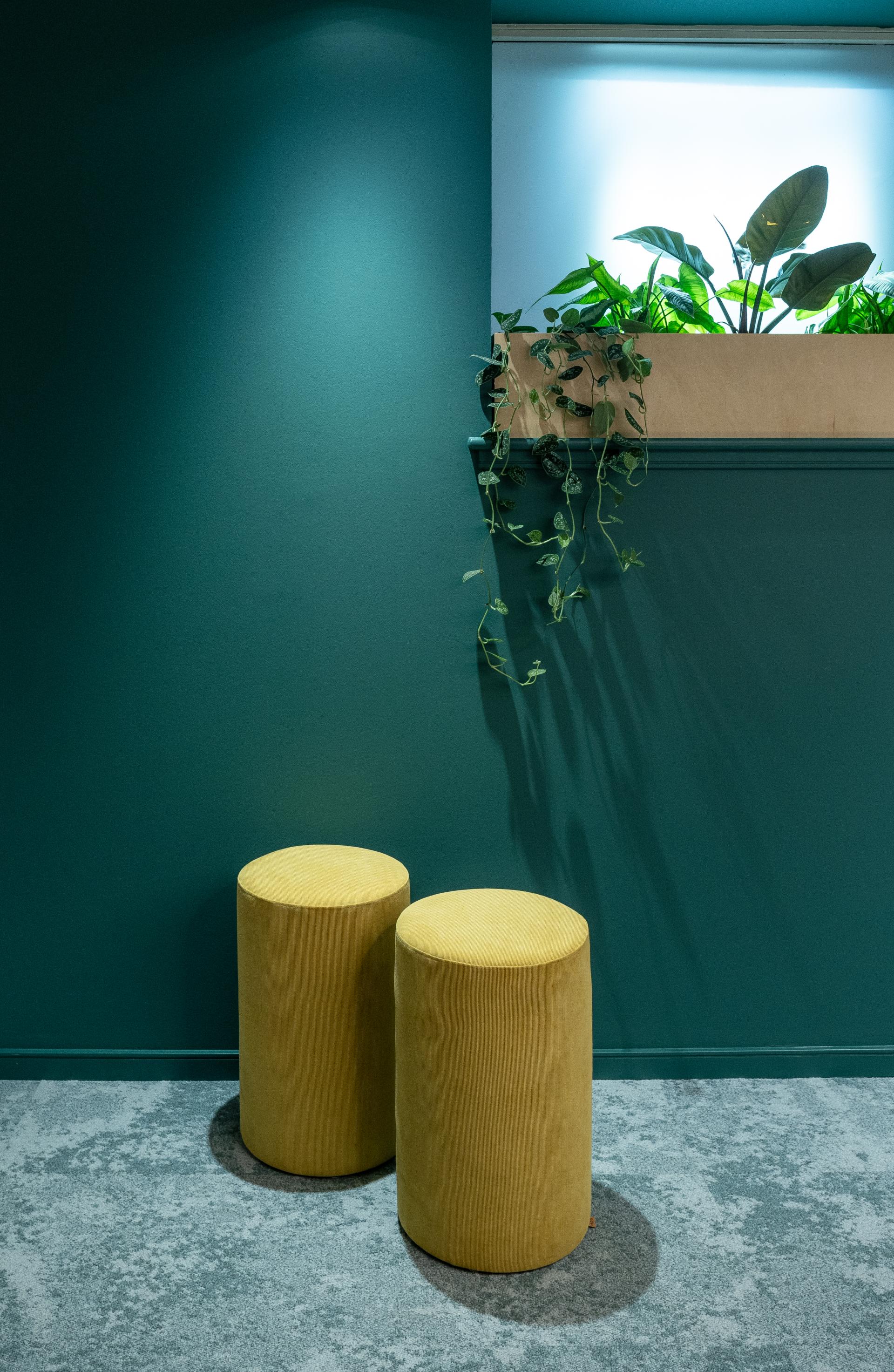 Stylish yellow stools in a vibrant green interior, showcasing a modern design for Scotland's built environment professionals.