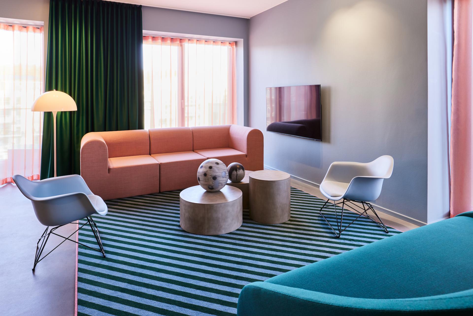 Stylish living area in Kirk Suites featuring vibrant Ege Carpets with bold striped patterns and modern furniture.