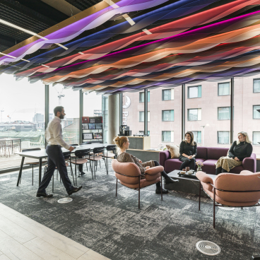 Modern office space at Riverside House, featuring vibrant ceiling design, comfortable seating, and collaborative work areas.