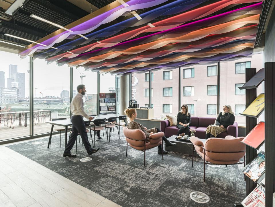 Modern office space at Riverside House, featuring vibrant ceiling design, comfortable seating, and collaborative work areas.