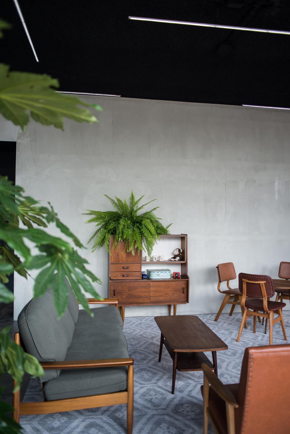 Minimalist interior design at HOP's Public Space featuring a plush sofa, vintage furniture, and greenery.