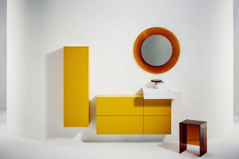 Stylish bathroom design featuring vibrant yellow cabinetry and a round mirror, blending Italian and Swiss aesthetics.