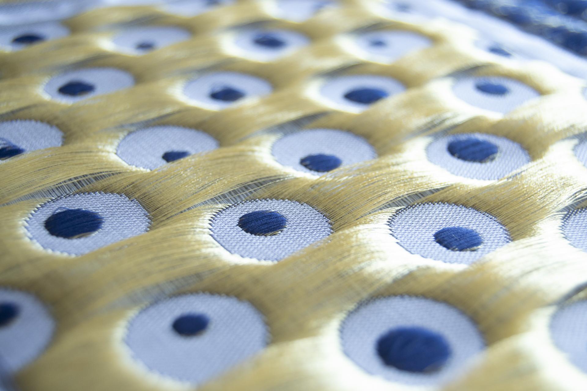 Intricate textile design featuring blue circles on a soft background, emphasizing sensory experience and biotechnologies in interior spaces.