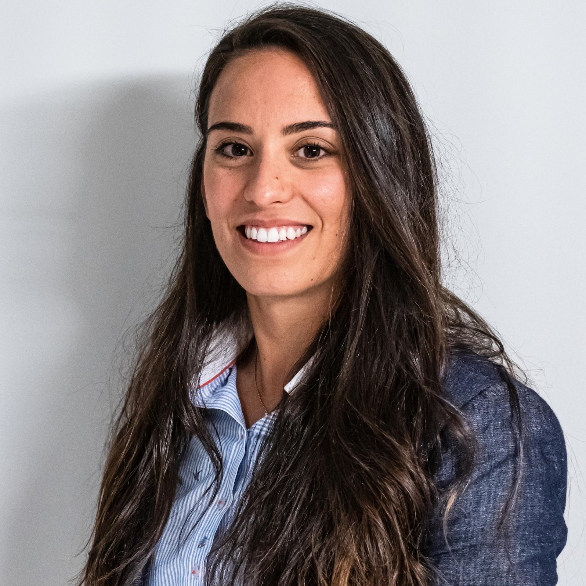 Professional woman with long hair, smiling, wearing a blue shirt, representing Manchester's evolving property market.