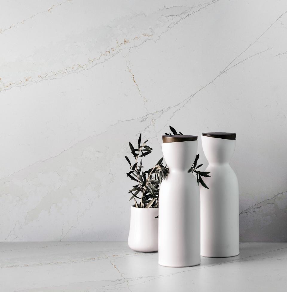 Elegant Silestone® Ethereal marble surface with contemporary white vases and olive branches, enhancing modern interior design aesthetics.