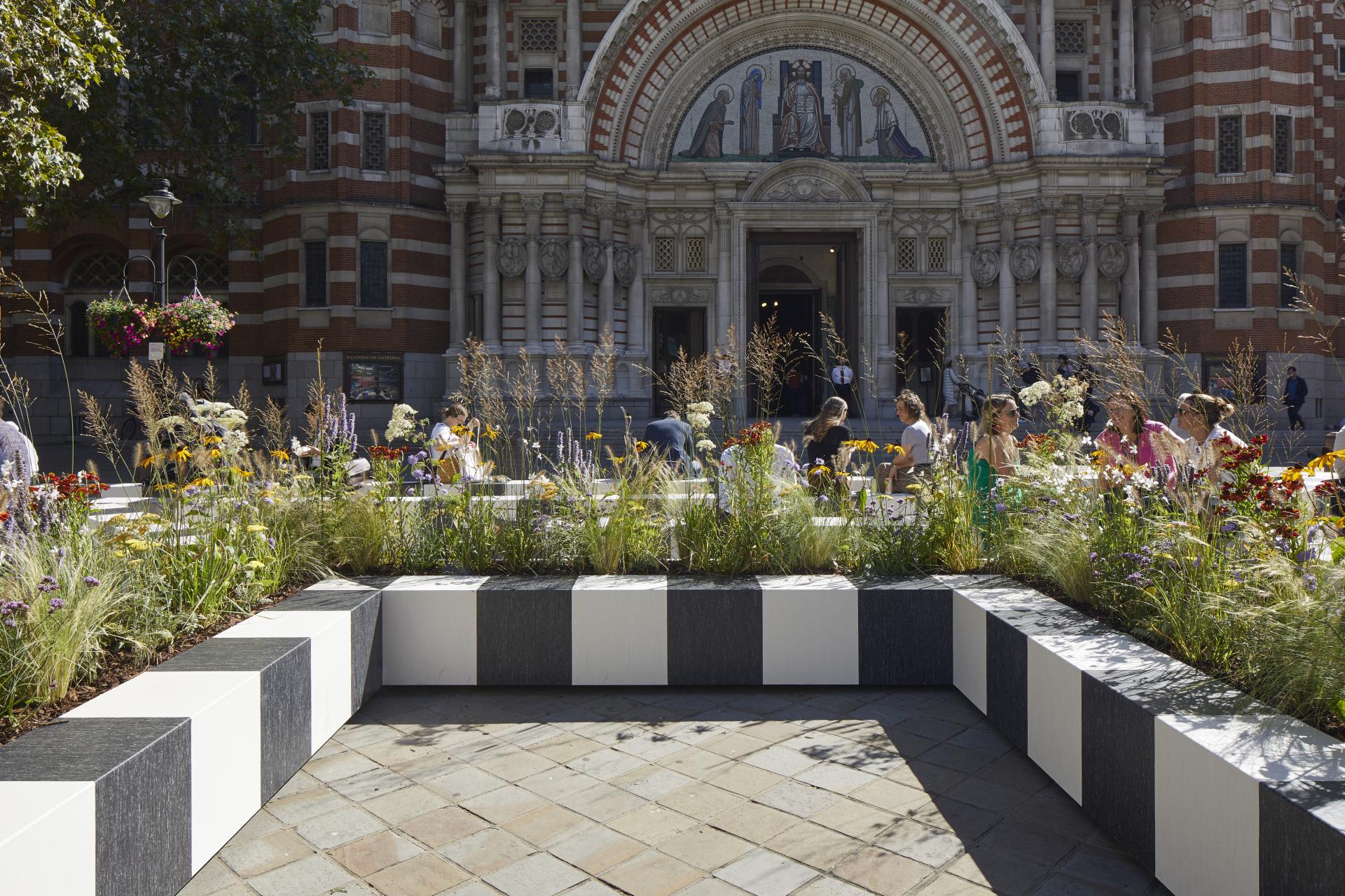A serene outdoor installation with floral arrangements and visitors engaging in a meditative experience at London Design Festival.