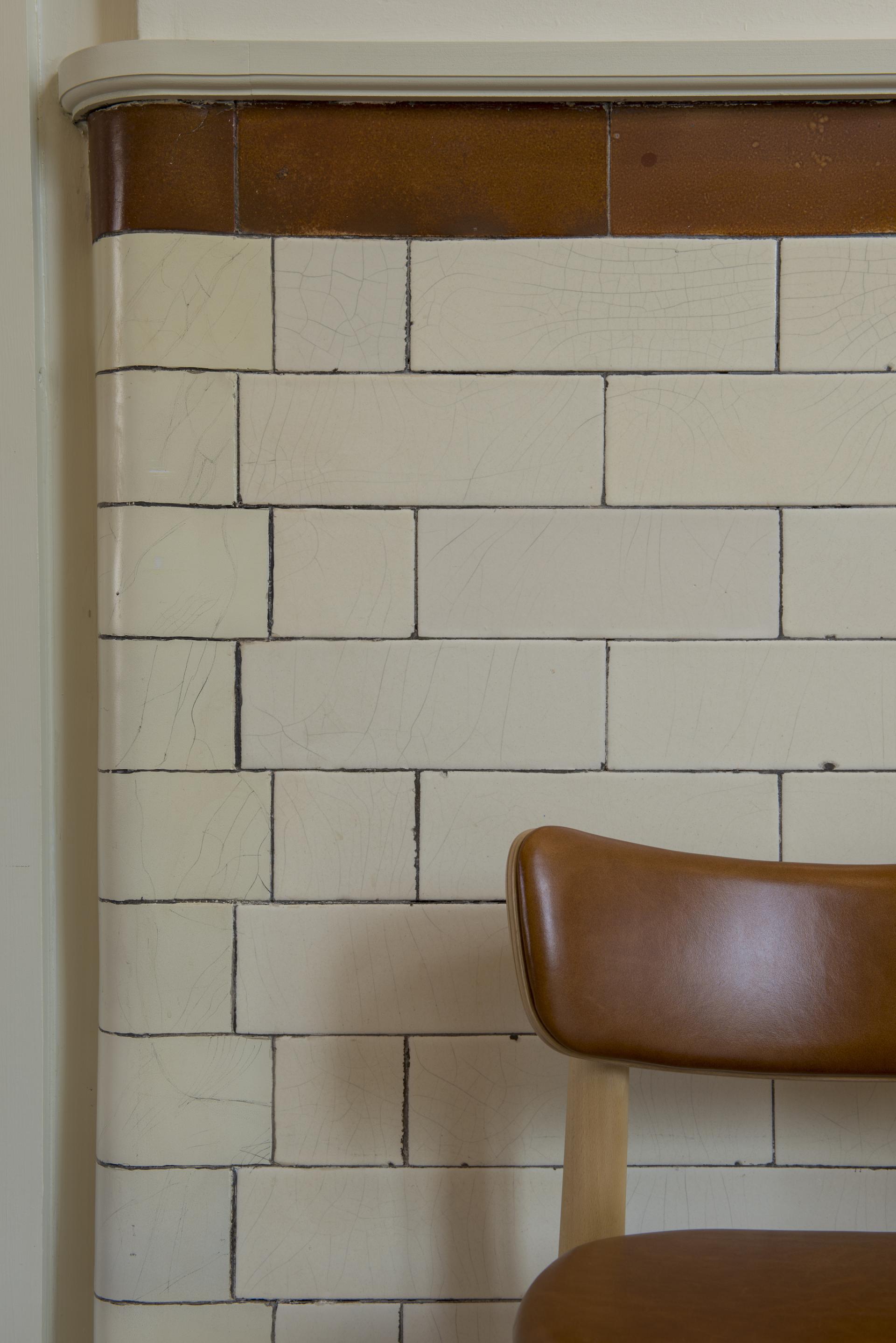 Stylish brown chair against a vintage tiled wall in the new Spicer & Cole concession at the Royal West of England Academy.