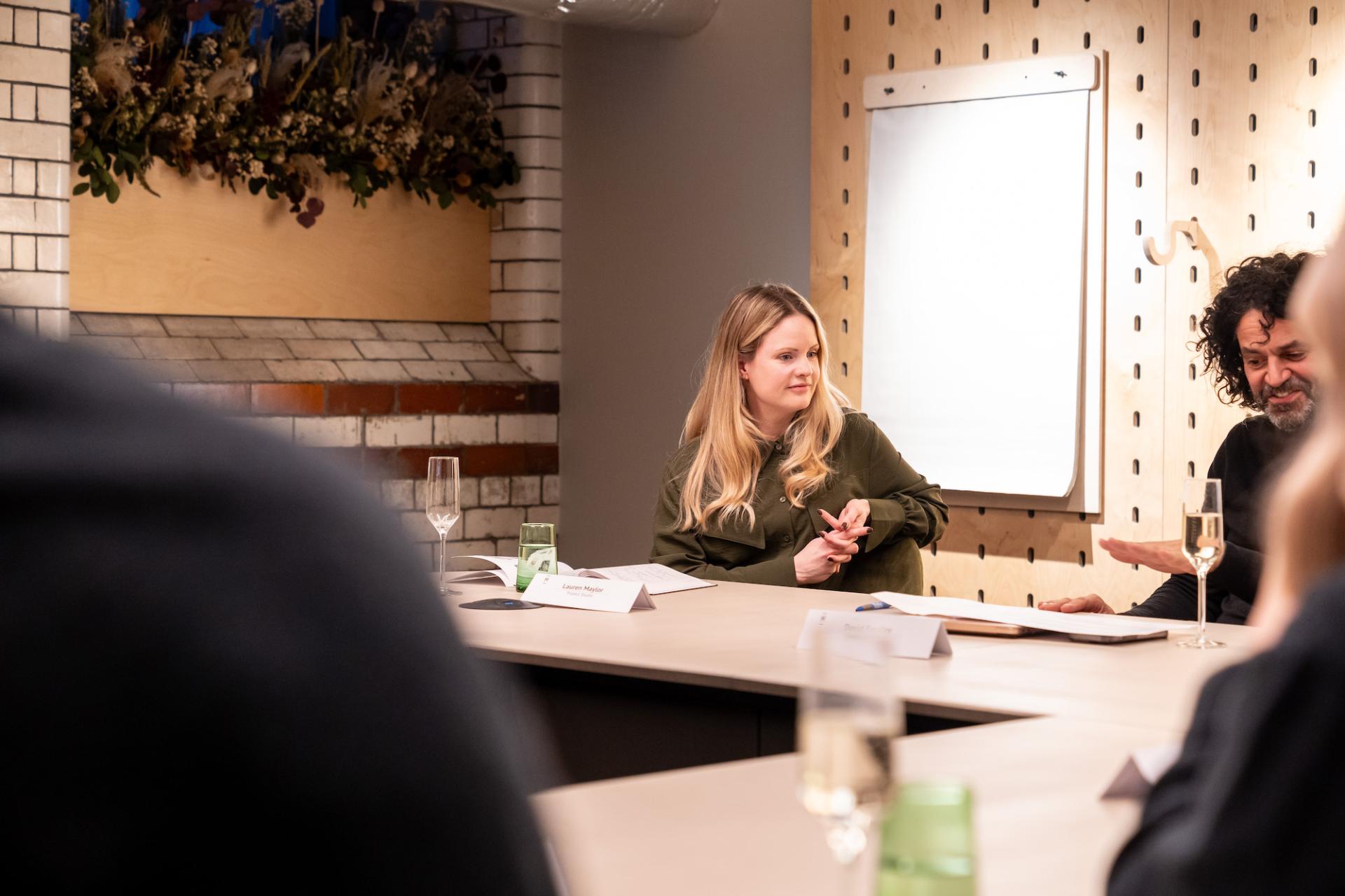 Participants engaged in a roundtable discussion on sustainability and value engineering in a well-lit meeting space.
