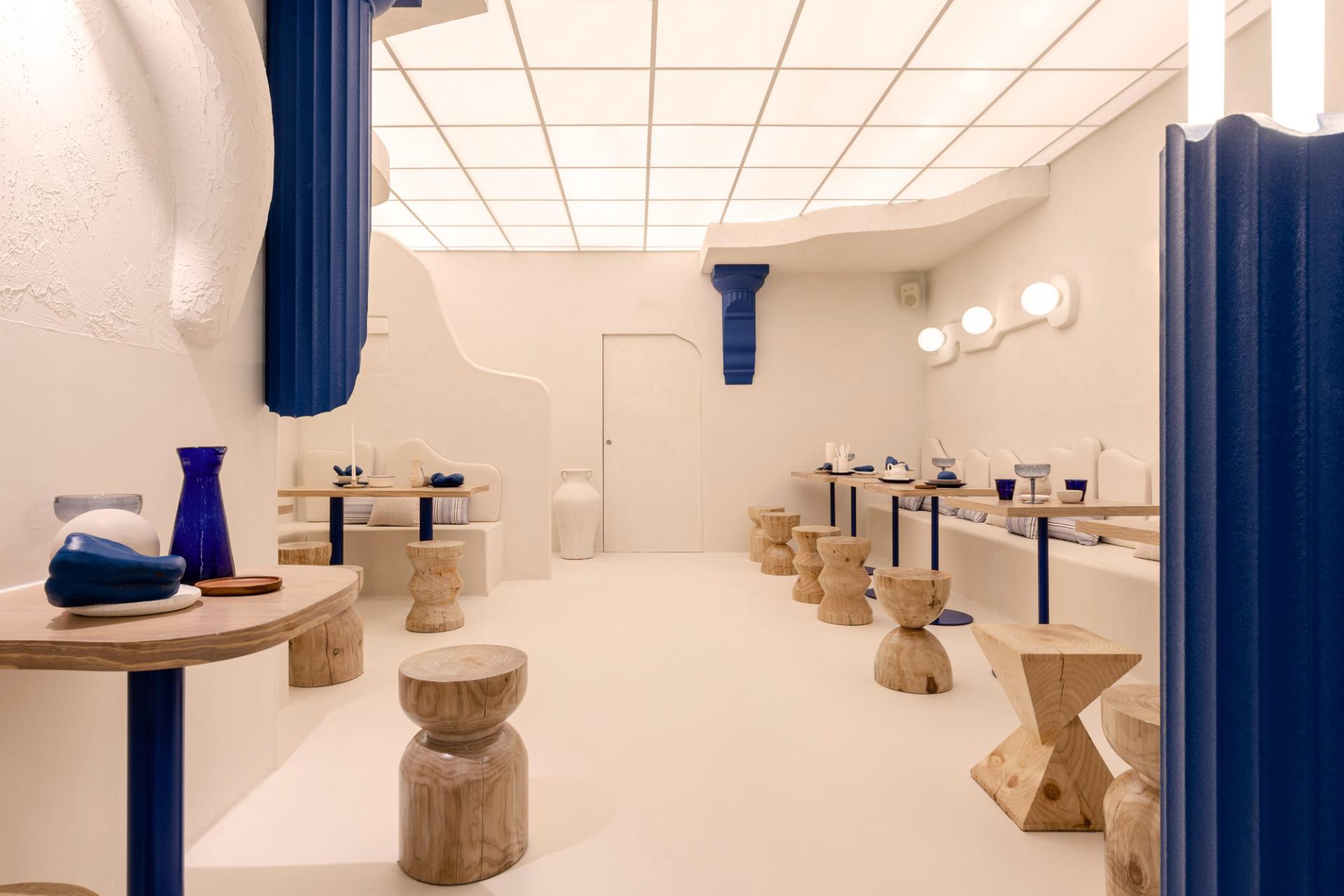 Bright, modern interior of Egeo restaurant featuring wooden tables, blue decor, and a minimalist design reflecting Greek aesthetics.
