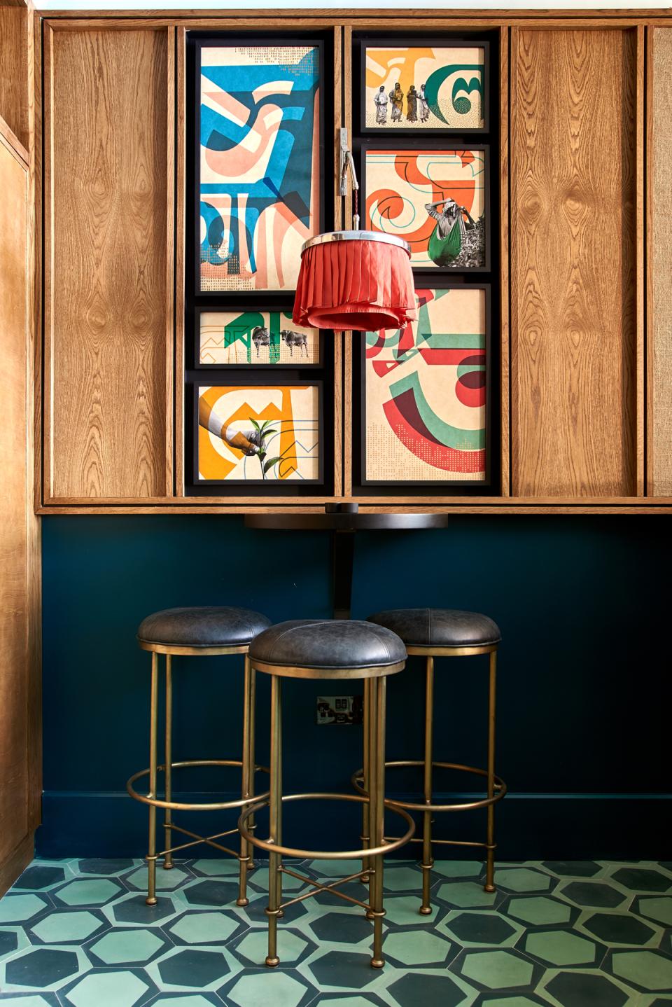 Stylish art deco decor featuring framed artwork, a red lamp, and modern bar stools in Teatulia's tea shop.