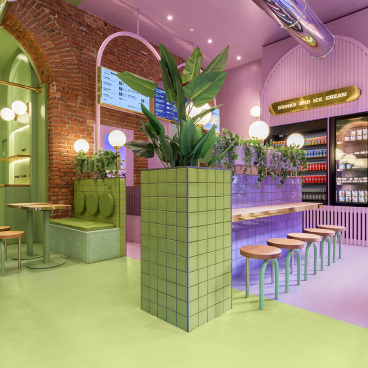 Vibrant candy-colored interior of Bun restaurant in Milan featuring green and purple tones, modern seating, and lush plants.