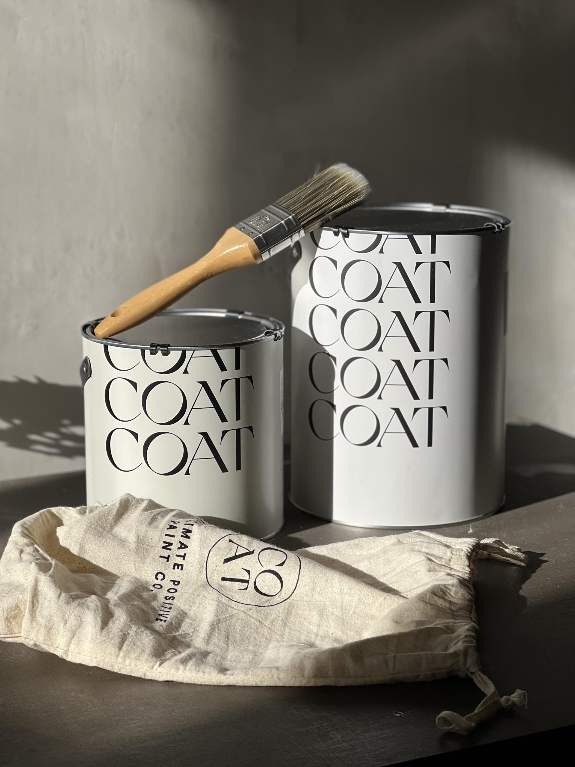 Two paint cans and a brush rest on a surface, showcasing modern design trends from Surface Design Show 2023.
