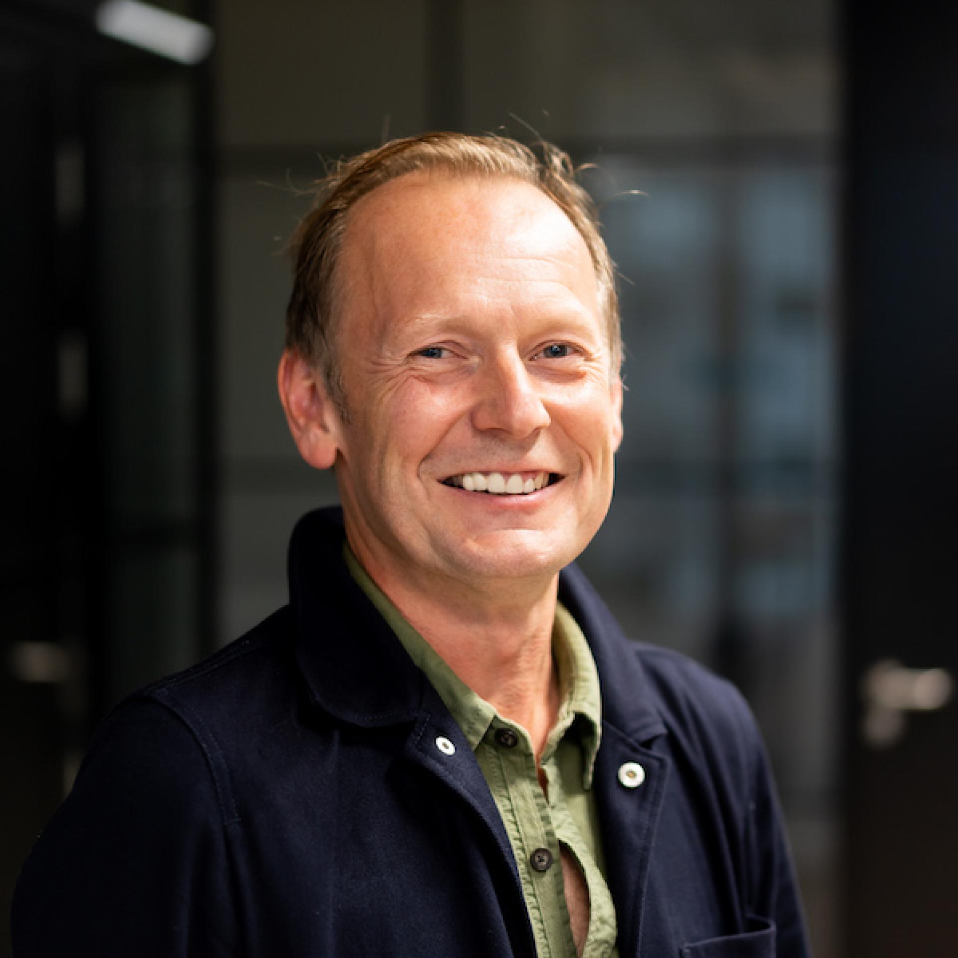 Smiling professional in a modern office, illustrating the human element of technology in forward-thinking workplaces.