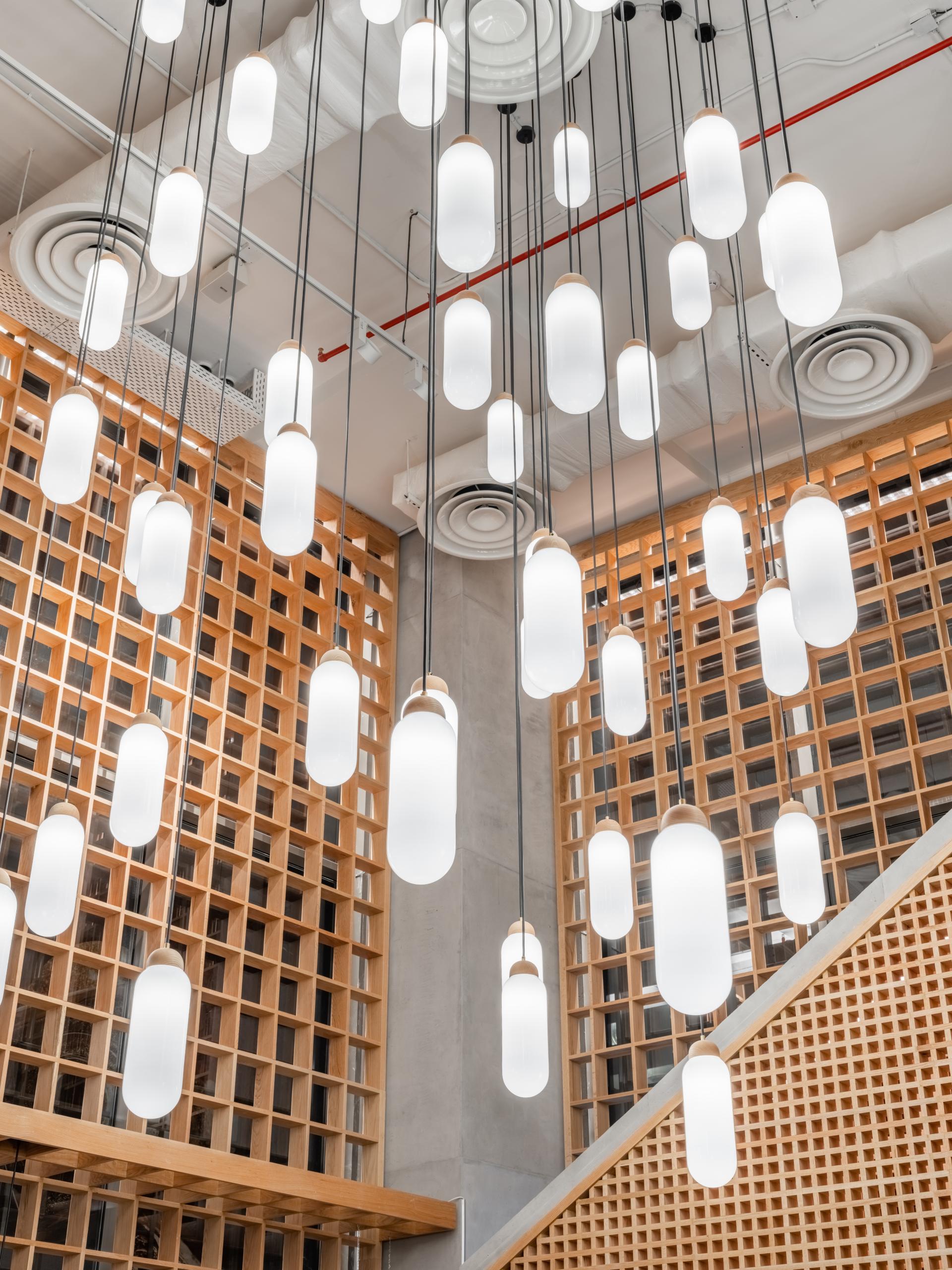 Suspended cylindrical lights illuminate the warm wooden accents, showcasing the Japandi aesthetic in Brew92’s new coffee shop design.