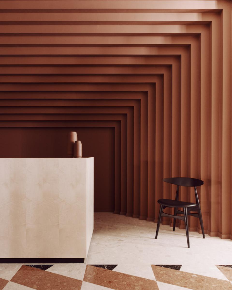 Contemporary workspace design featuring a textured brown wall, minimalist reception desk, and stylish black chair at Summit House.