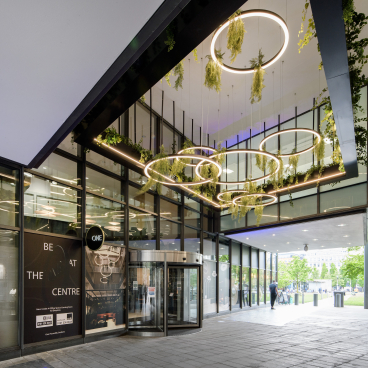 Modern entrance of One Piccadilly Gardens featuring stylish circular lights and greenery, transformed by Manchester’s SpaceInvader.