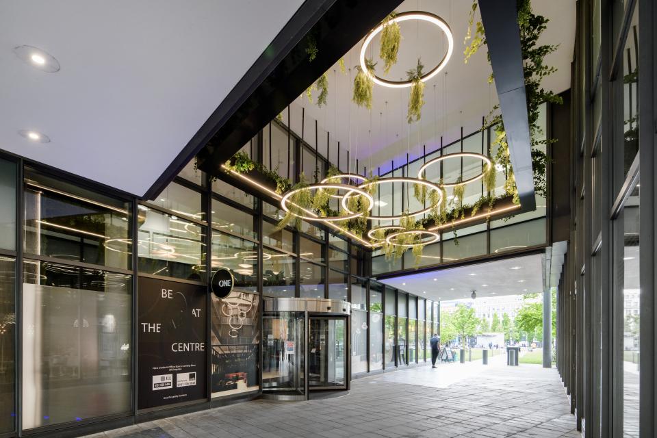 Modern entrance of One Piccadilly Gardens featuring stylish circular lights and greenery, transformed by Manchester’s SpaceInvader.