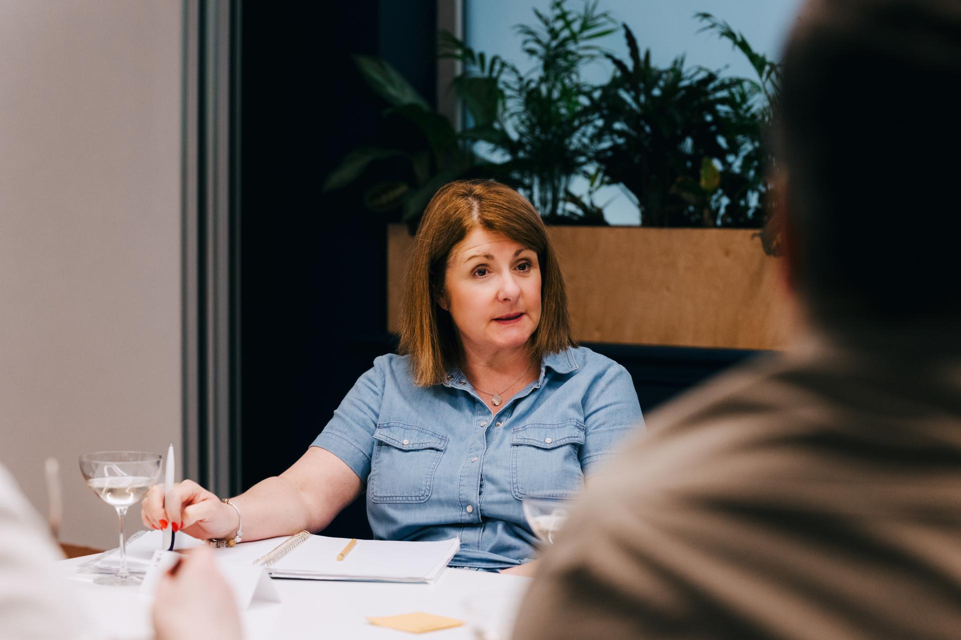Roundtable discussion on neurodiversity at Material Source Studio, featuring a woman speaking thoughtfully in a collaborative setting.