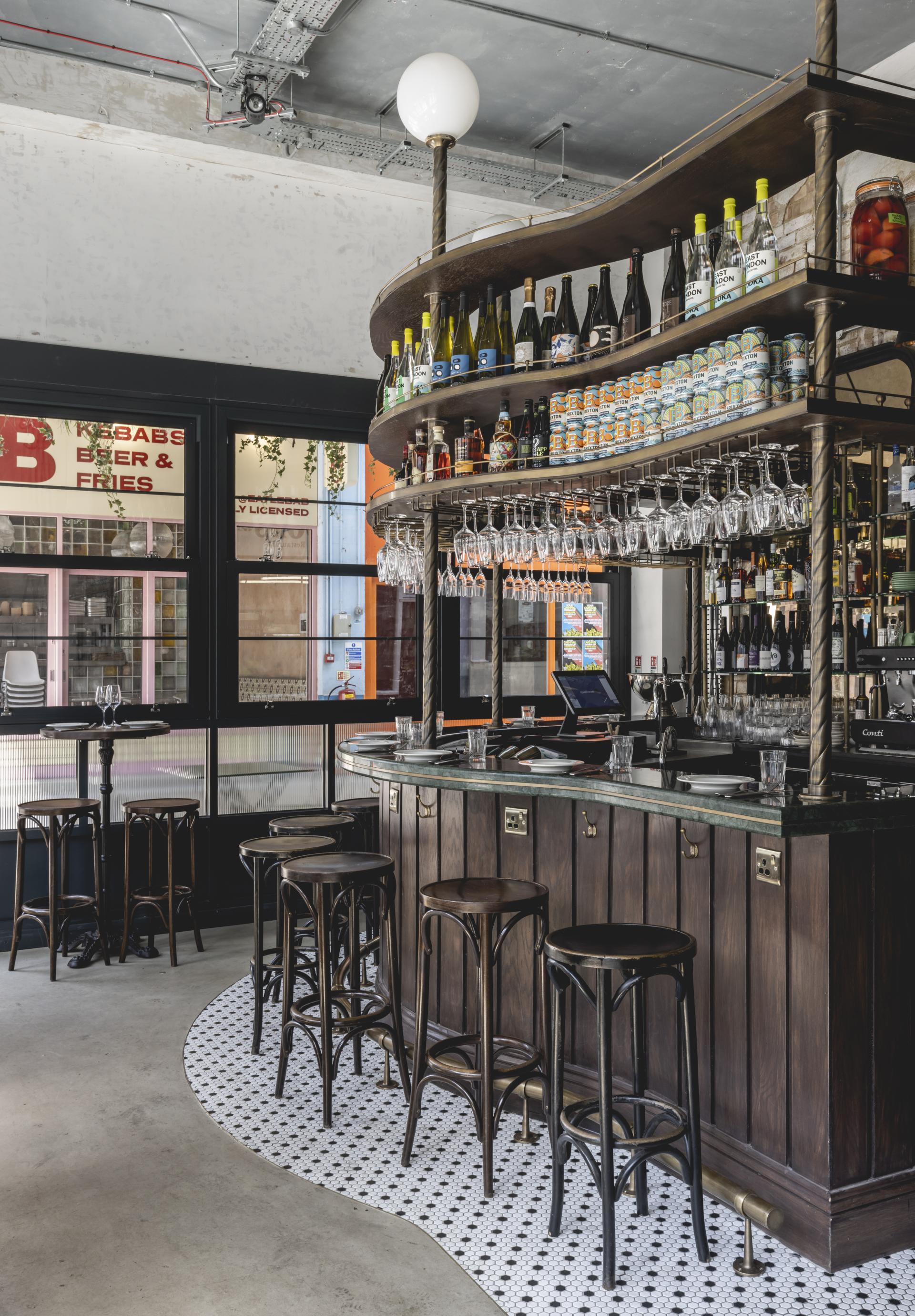 Stylish wine bar interior with a wooden counter, shelves of drinks, and modern seating, inspired by Parisian designs.