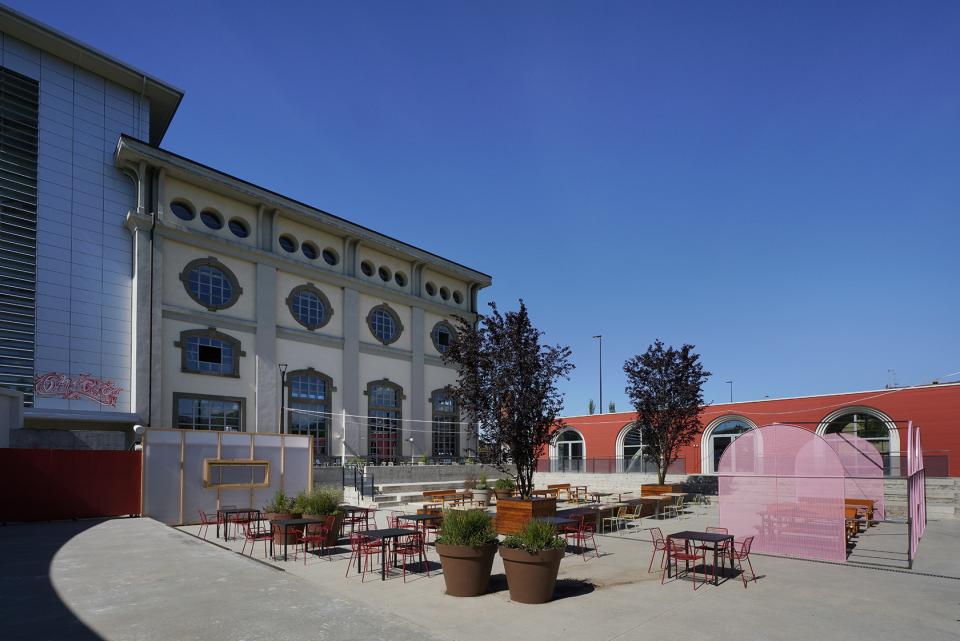Redeveloped former thermal power plant in Bergamo, featuring outdoor seating areas and modern architecture in a vibrant community space.