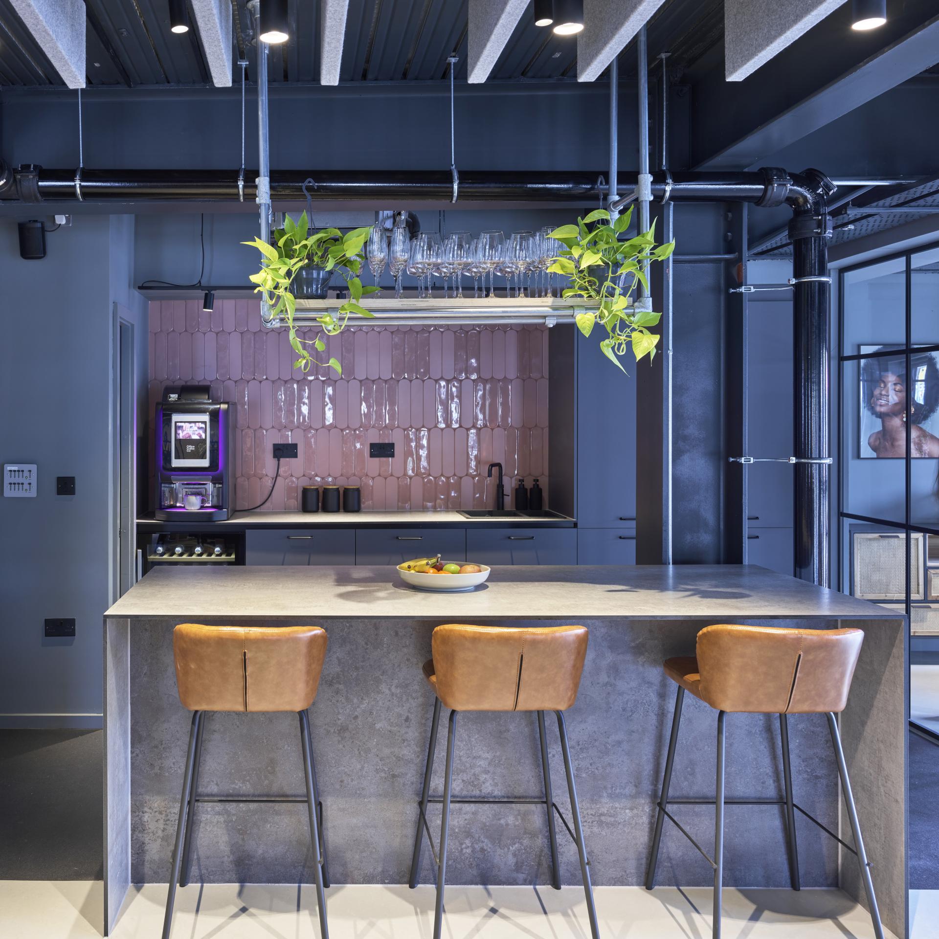 Modern kitchen design featuring a concrete bar, leather stools, and a stylish background, reflecting J’adore Models' new HQ.