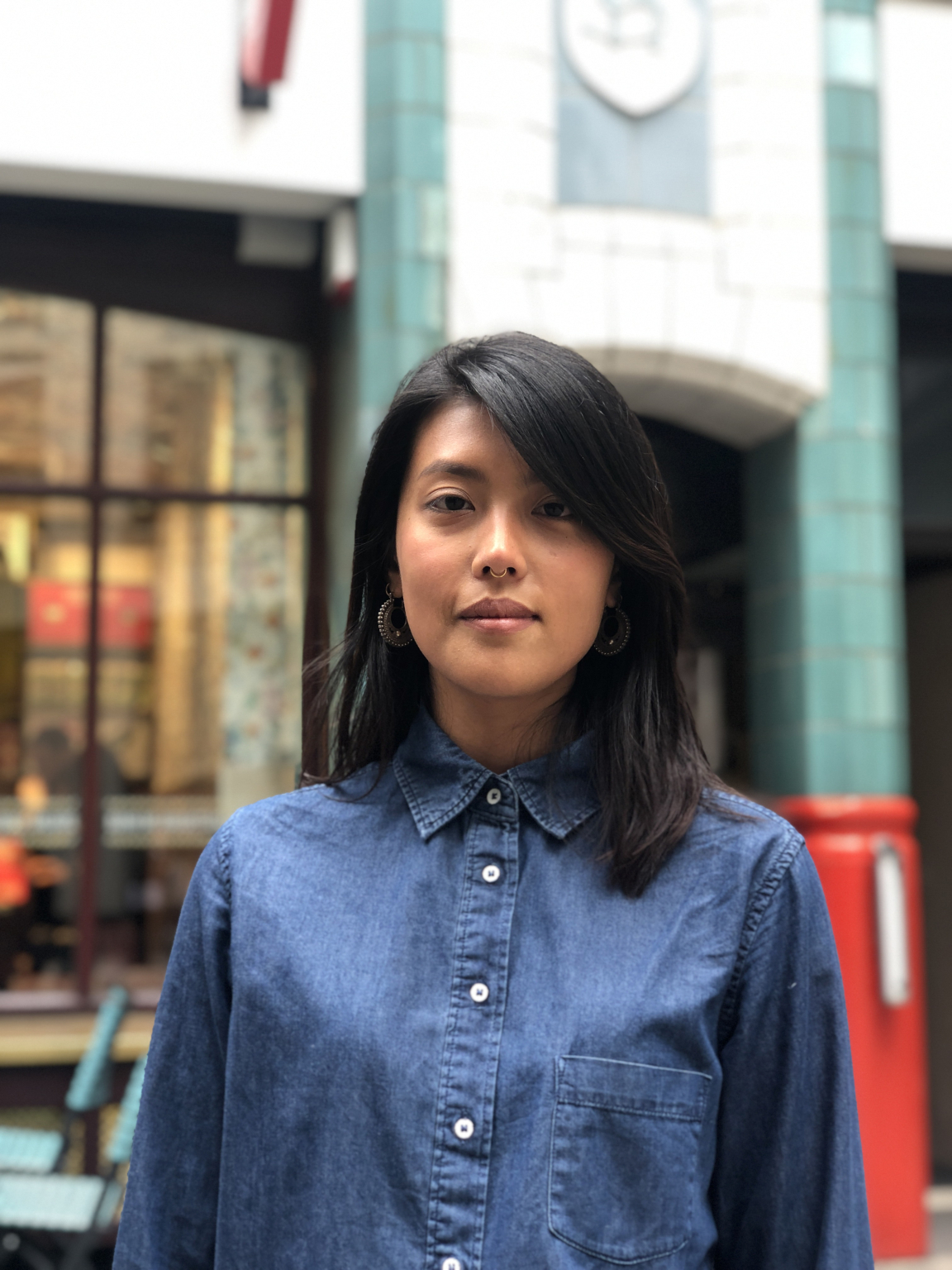 Carmellia Indrawati, an Indonesian designer, poses in a blue shirt, embodying her unique cultural perspective in design.