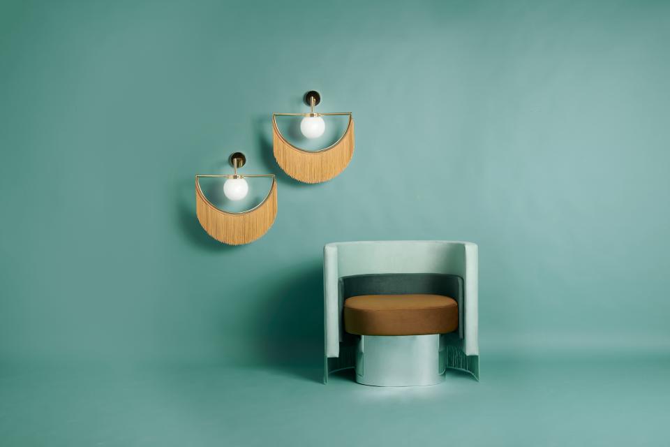 Vintage-inspired chair with brown cushion and stylish wall sconces featuring spherical bulbs against a teal background.