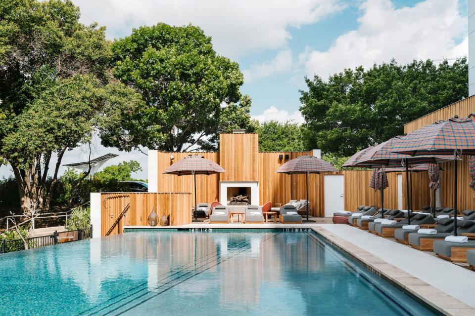 Lush pool area featuring natural wood designs and stylish umbrellas at a renovated mid-century hotel in Austin.