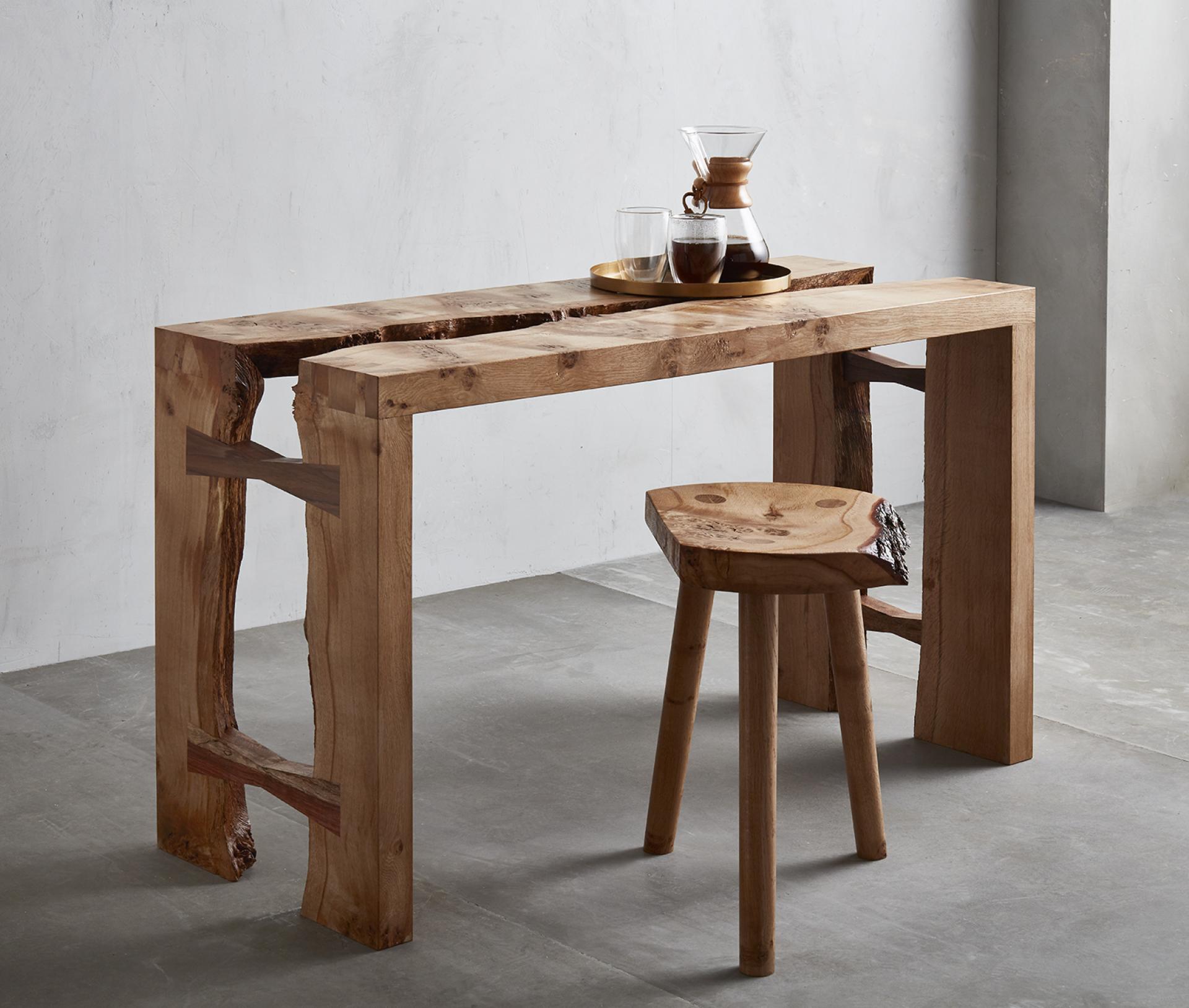 Artisan wooden table and stool showcasing natural beauty, handcrafted by Takumi Woodwork in a minimalist workshop setting.