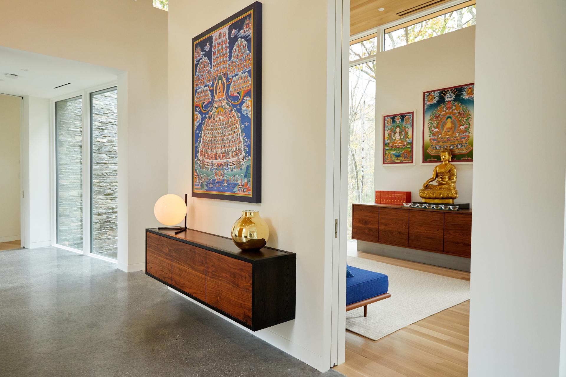 Spacious interior featuring modern decor, traditional artworks, and a golden Buddha statue in a serene Brooklyn setting.