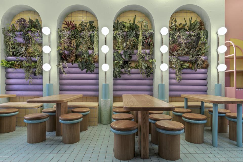 Lively interior of Piada’s second shop in Lyon, featuring pastel colors, wooden tables, and a lush plant wall.